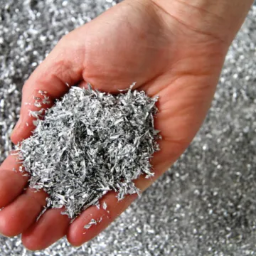 A handful of clean aluminum milling chips, solid swarf rather than airborne grinding dust