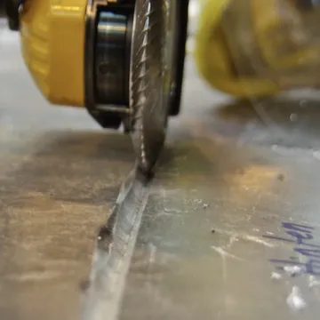 A milling disc on an angle grinder cutting a clean V-groove into an aluminum plate