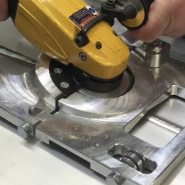 Milling disc dressing a curved aluminum part held in a bench fixture